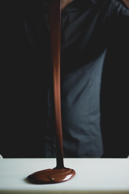 midsection of man pouring melted chocolate on table