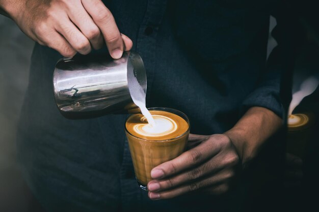 Foto sezione centrale di un uomo che versa latte in una tazza di caffè