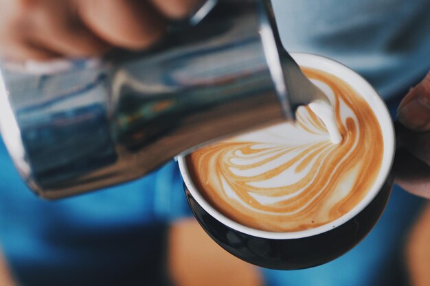 Photo midsection of man pouring milk on coffee cup