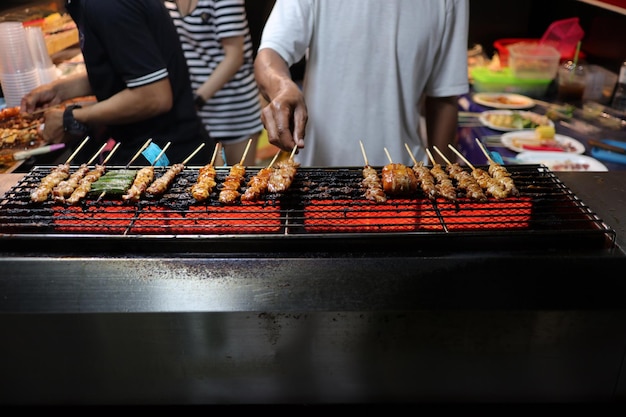 Foto sezione centrale di un uomo che prepara il cibo su una griglia da barbecue