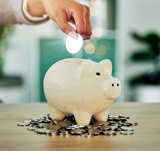 Photo midsection of man putting coin in piggy bank
