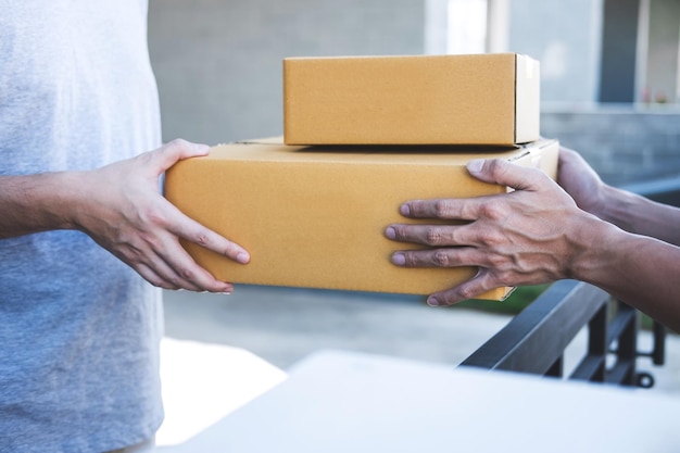 Midsection of man receiving boxes from delivery person at entrance