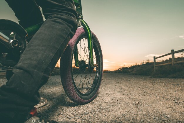 Sezione centrale di un uomo in bicicletta contro il cielo durante il tramonto