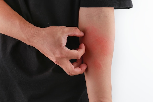 midsection of man scratching while standing against white background