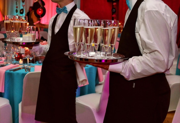 Foto sezione centrale di un uomo che serve bicchieri di champagne.