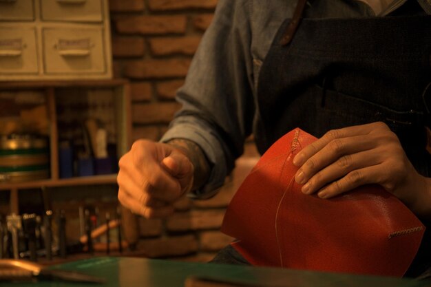 Photo midsection of man sewing leather in workshop