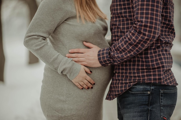 Foto sezione centrale di un uomo che tocca lo stomaco di una donna incinta mentre è in piedi all'aperto