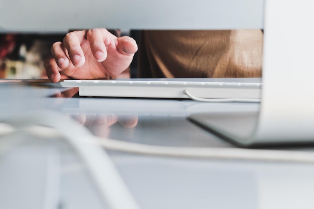 midsection of man using computer on desk in office