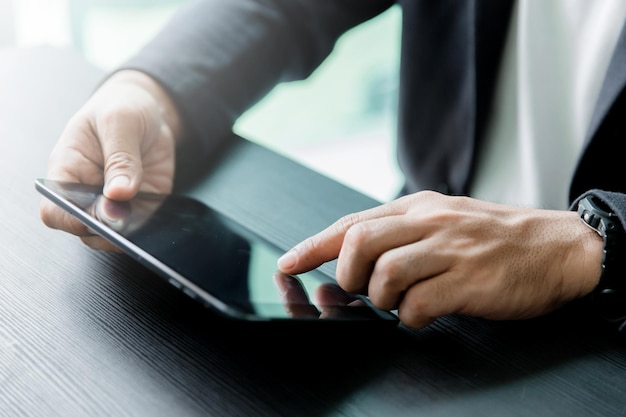 midsection of man using digital tablet at table