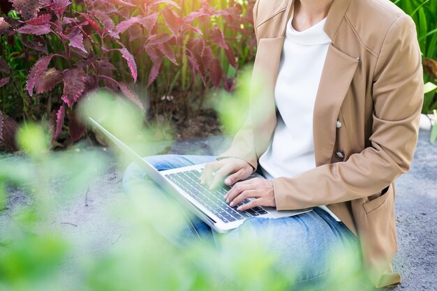 Midsection of man using laptop while sitting amidst plants