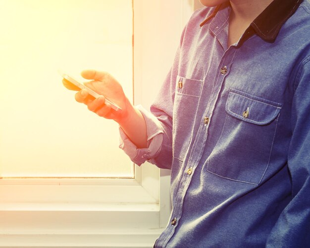 Midsection of man using mobile phone by wall