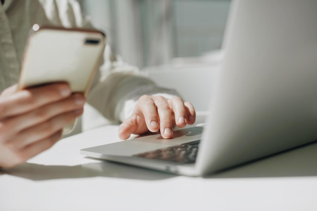 Midsection of man using mobile phone and laptop on table