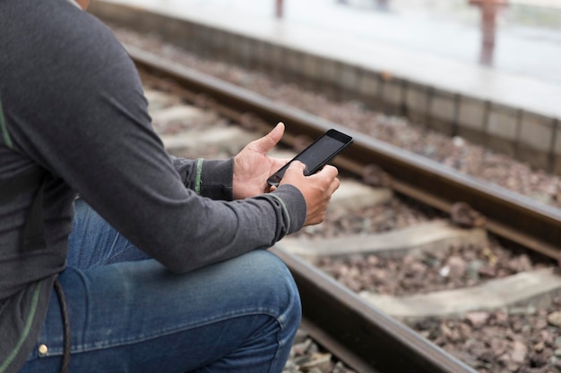 Midsection of man using mobile phone on railroad station