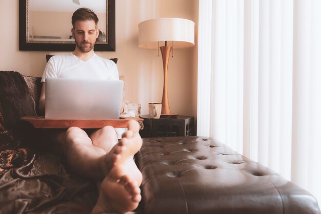 Midsection of man using mobile phone while sitting on bed