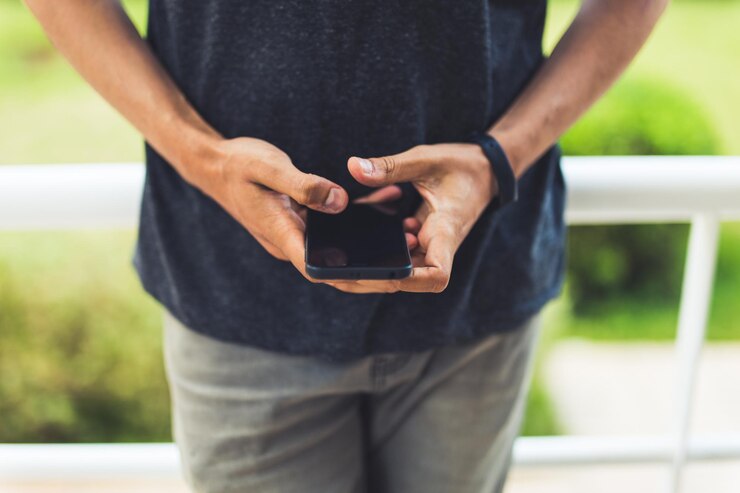 Photo midsection of man using mobile phone while standing by railing in balcony