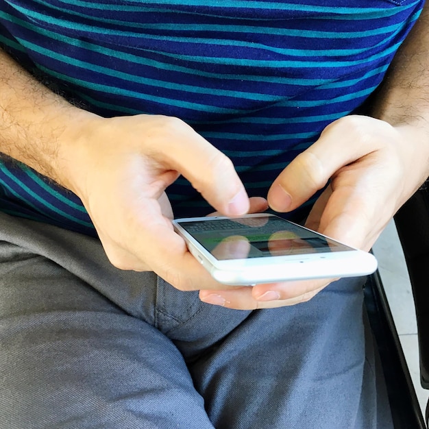 Foto sezione centrale di un uomo che usa il telefono mentre è seduto sul sedile