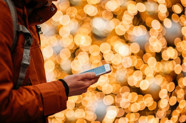 Midsection Of Man Using Smart Phone Against Illuminated Christmas Tree.