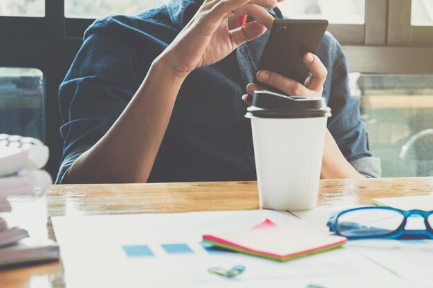 Photo midsection of man using smart phone while sitting at office