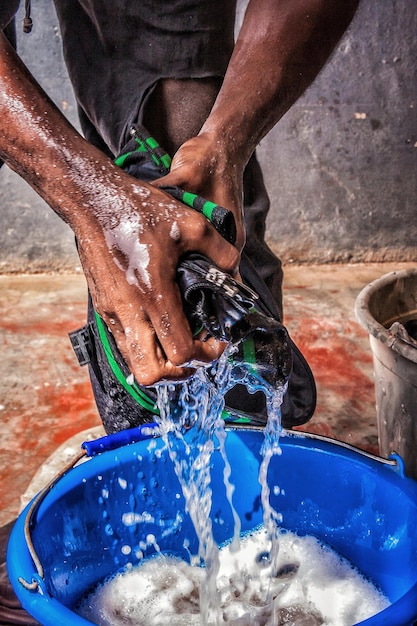 midsection of man washing cloth in bucket