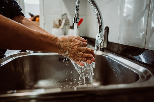 Midsection of man washing hands in sink