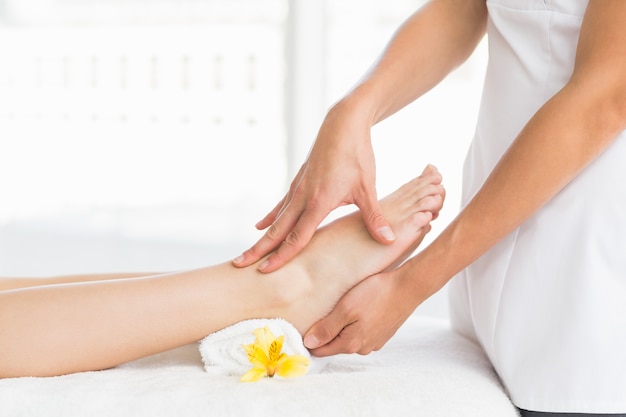 Midsection of masseur giving foot massage to woman