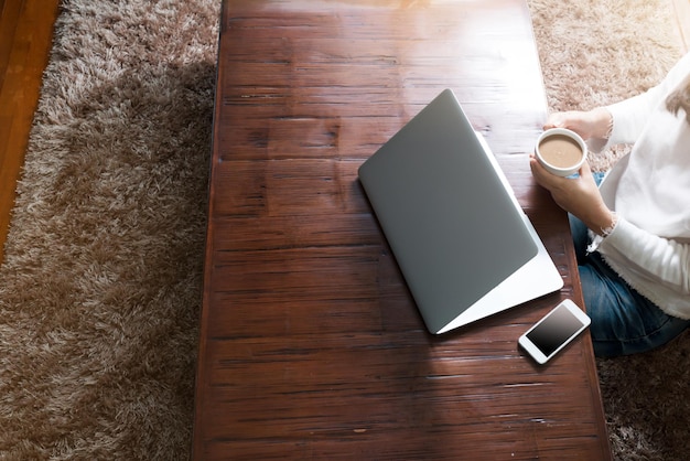 Midsection of mature woman holding coffee cup at table