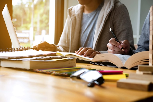 Photo midsection of men reading book while sitting on table