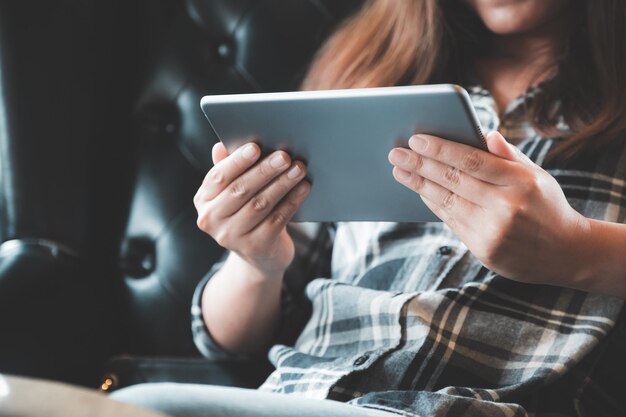 Photo midsection of mid adult woman using digital tablet while sitting at home