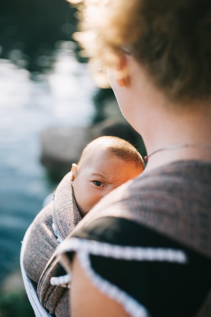 Photo midsection of mother carrying daughter in baby carrier