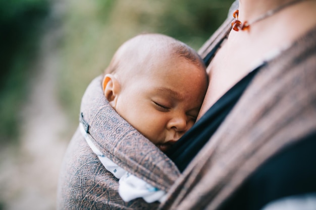 Photo midsection of mother carrying sleeping daughter in baby carrier