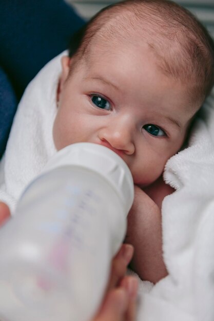 Photo midsection of mother feeding son with milk bottle