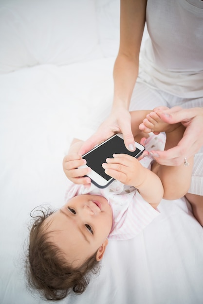 Midsection of mother holding mobile phone while playing with baby 