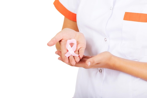 Midsection of nurse holding pink ribbon against white background