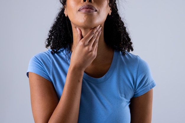 Фото Живот африканской американки среднего возраста, касающейся болезненного горла на белом фоне. копировать пространство, горло, щитовидную железу, медицину, боль, болезнь и концепцию здравоохранения.