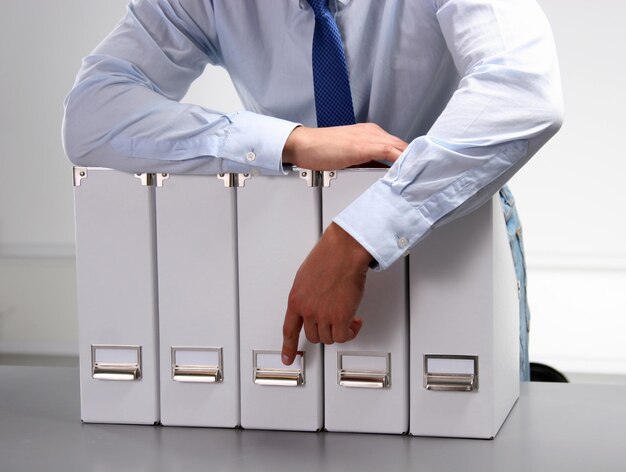 Фото Средняя часть бизнесмена, держащего небольшие шкафчики в офисе
