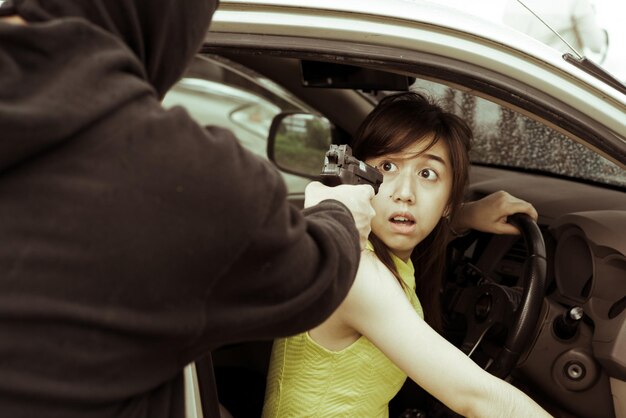 写真 車に座っている怖い女性に銃を向けた犯罪者のミッドセクション