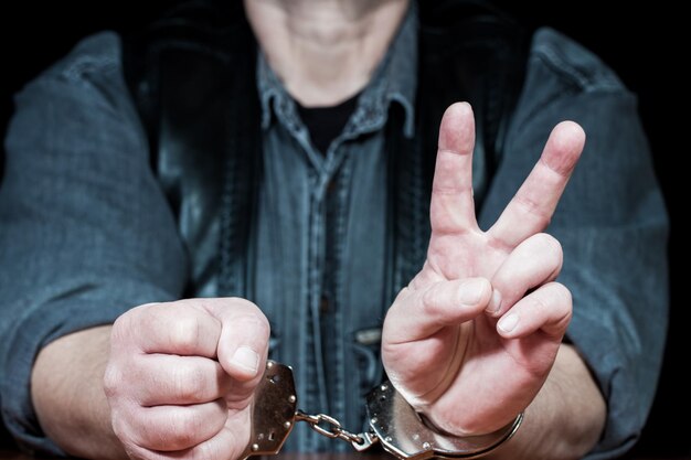사진 감옥 에 앉아 평화 의 표지 를 보여 주는 범죄자 의 중간 부분