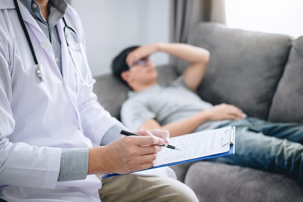 写真 ソファに横たわっている患者によってチェックリストを記入する医師のミッドセクション