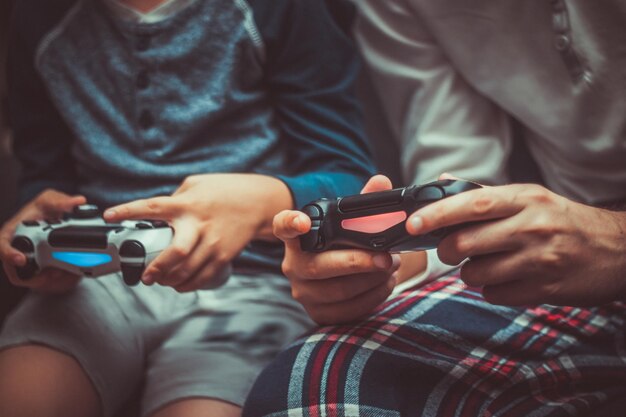 写真 家でビデオゲームをしている父と息子のミッドセクション