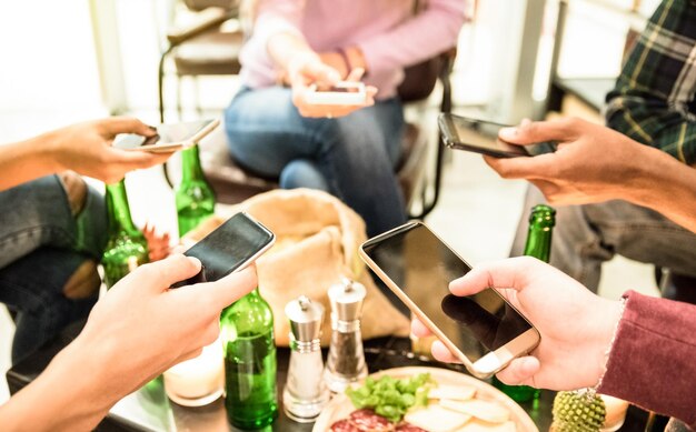 写真 レストランに座っている間携帯電話を使っている友達のミッドセクション