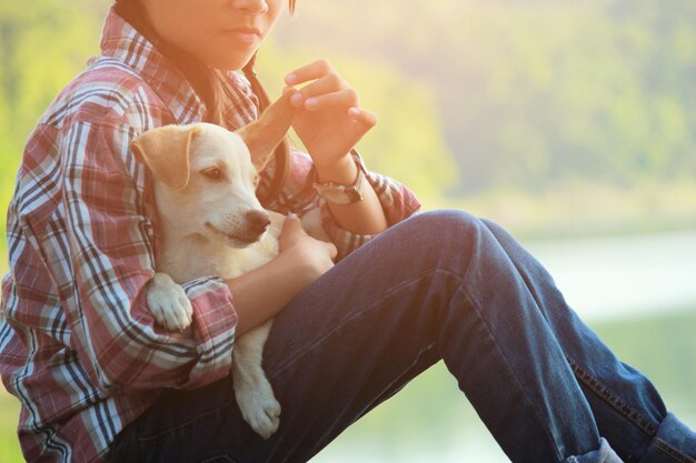 写真 岩の上に座っている子犬と遊んでいる女の子のミッドセクション