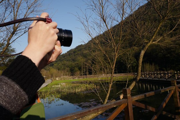 写真 空の向こうの川で写真を撮っている男性のミッドセクション