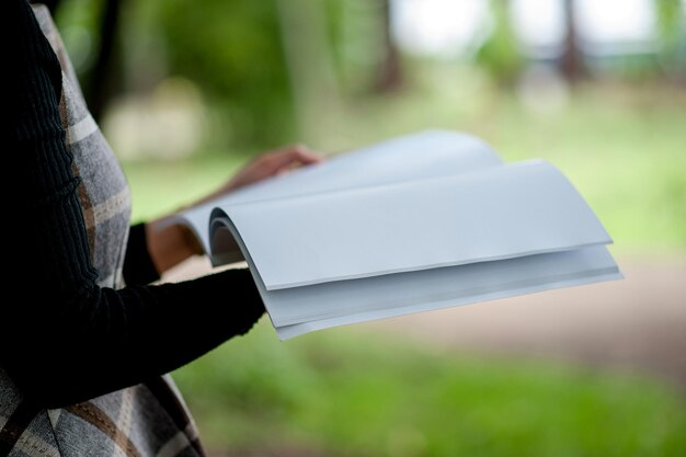 写真 外で立っている間白い本を握っている女性のミッドセクション