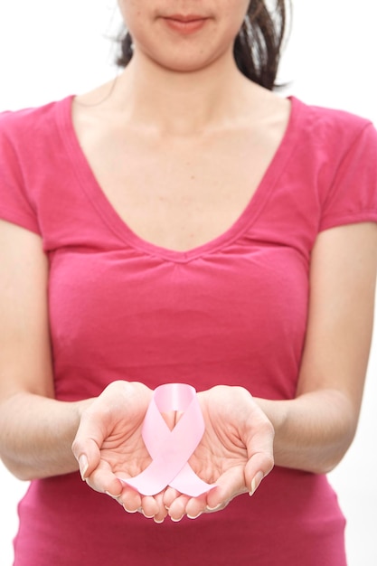 写真 白い背景に乳がんに対する意識のリボンを握っている女性の中央部分