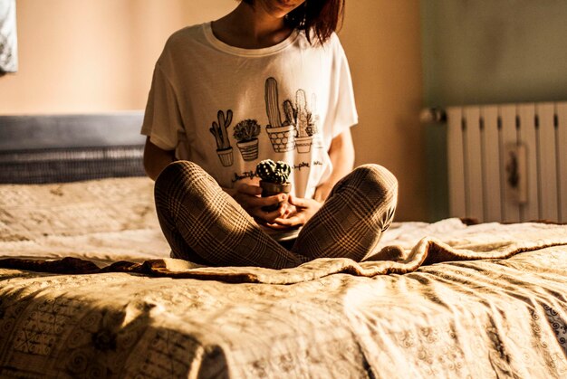 사진 집 에서 침대 에 앉아 있는 여자 가 토스 를 들고 있는 중간 부분