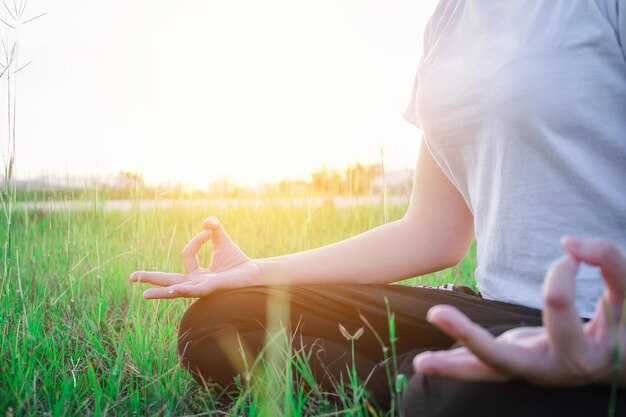 Фото Средняя часть женщины, выполняющей йогу, сидящей на поле против неба