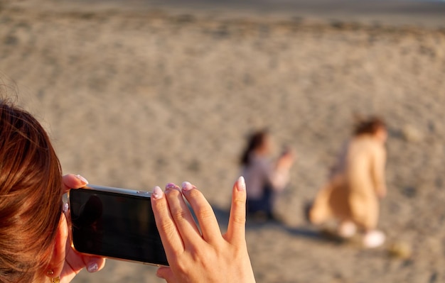 사진 해변 에서 휴대 전화 로 사진 을 찍는 여자 의 중간 부분