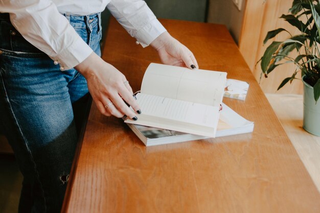 写真 テーブルの上で本を読んでいる女性のミッドセクション