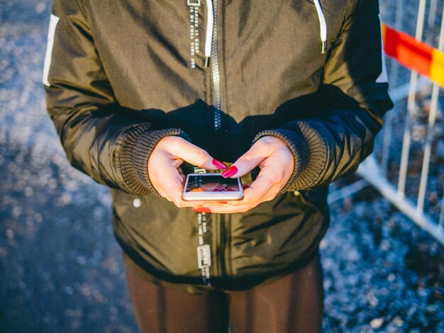 写真 道路で携帯電話を使っている女性のミッドセクション