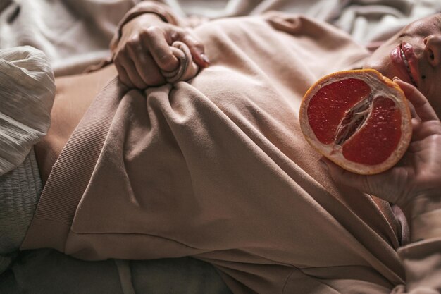 Фото Секция женщины с грейпфрутом, лежащей в постели дома